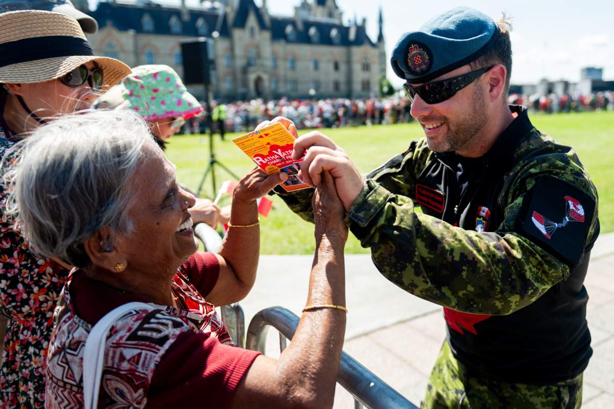 Mobile Support Equipment Operator and Demonstrator Cpl. Dominic Raymond of 3 Wing, CFB Bagotville, right, shares a moment with a guest following his successful SkyHawks jump over Parliament Hill during Canada Day celebrations in Ottawa, on Monday, July 1, 2024. THE CANADIAN PRESS/Spencer Colby