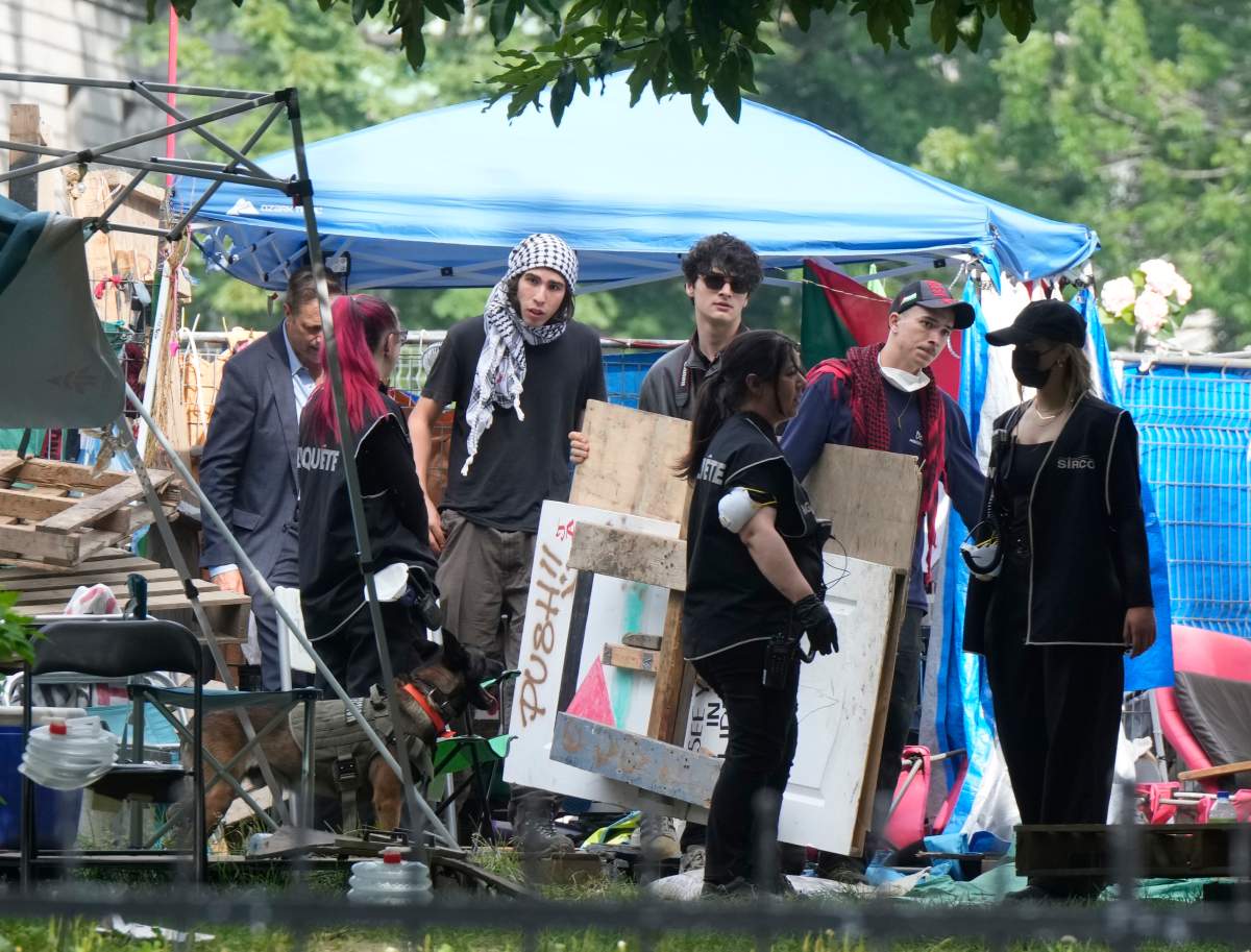 Protesters move signs as security clears the pro-Palestinian encampment at McGill University in Montreal, Wednesday, July 10, 2024.