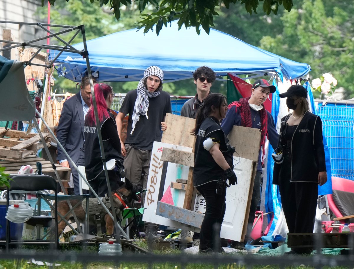 Protesters move signs as security clears the pro-Palestinian encampment at McGill University in Montreal, Wednesday, July 10, 2024.