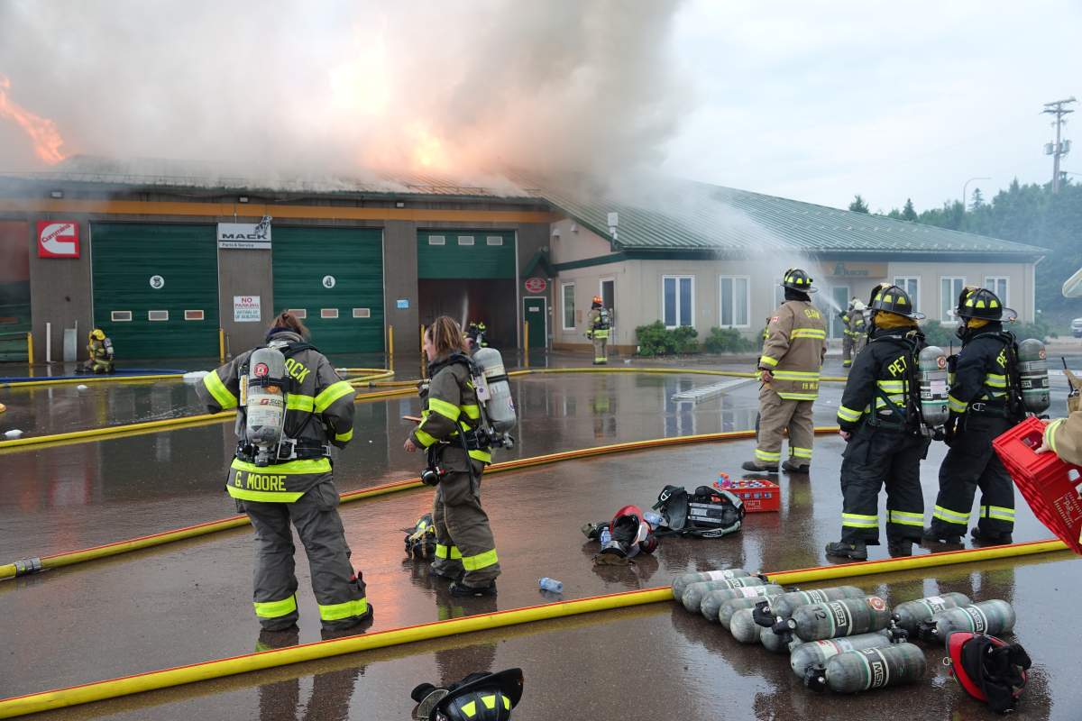 Firefighters in front of a trucking business on fire.