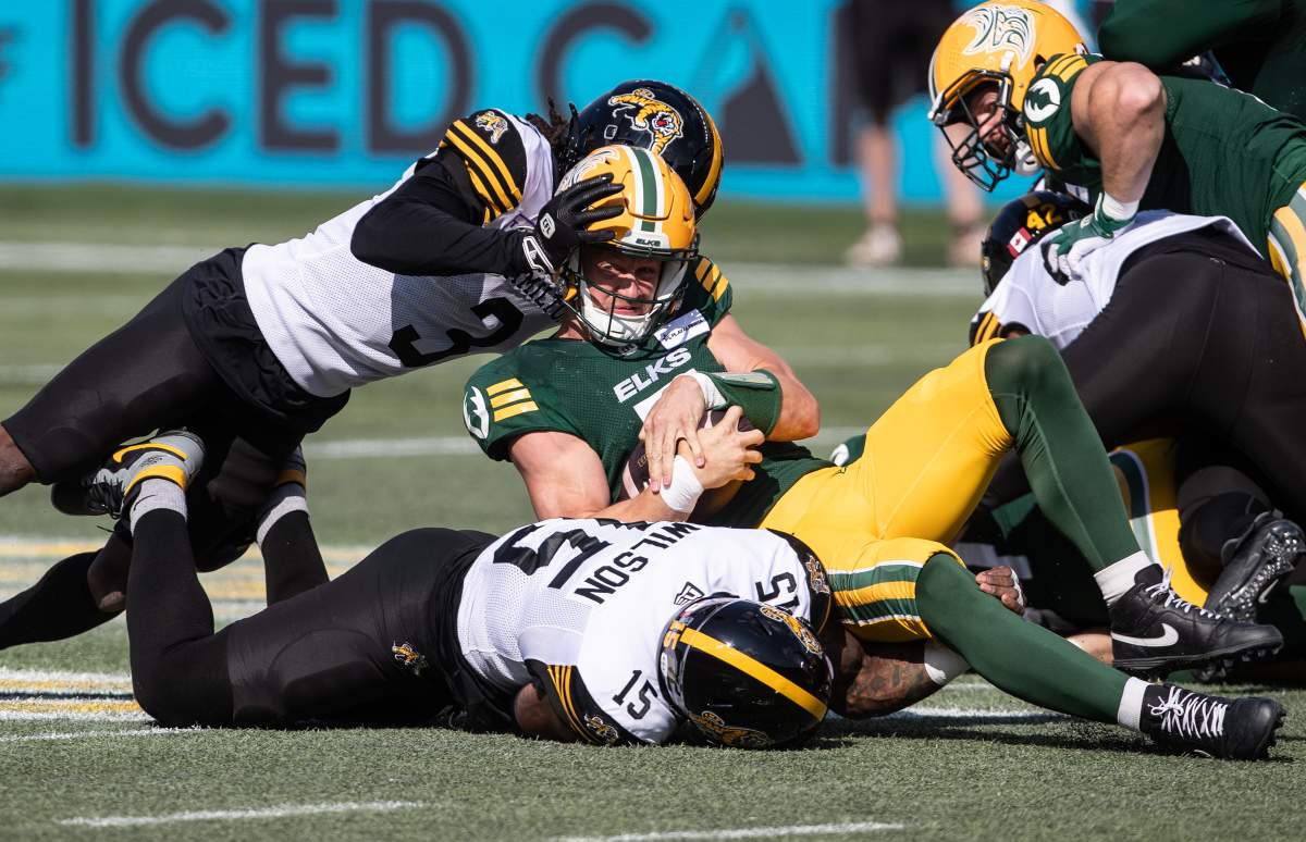 Hamilton Tiger-Cats' Kenneth George Jr. (3) and David Beard (51) tackle Edmonton Elks quarterback Dakota Prukop (7) during first half CFL action in Edmonton, Sunday, July 28, 2024.