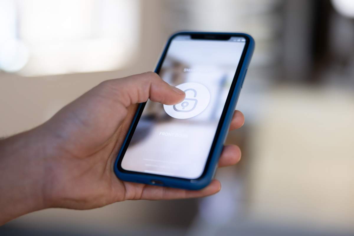 Close-up on a man locking his house using a home automation app on his cell phone.