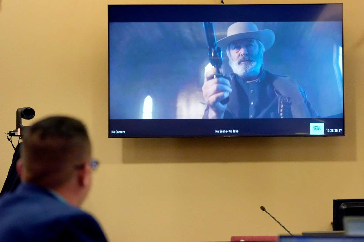 A still of Alec Baldwin, dressed like a Western cowboy holding a gun, is seen on a TV in the courtroom.