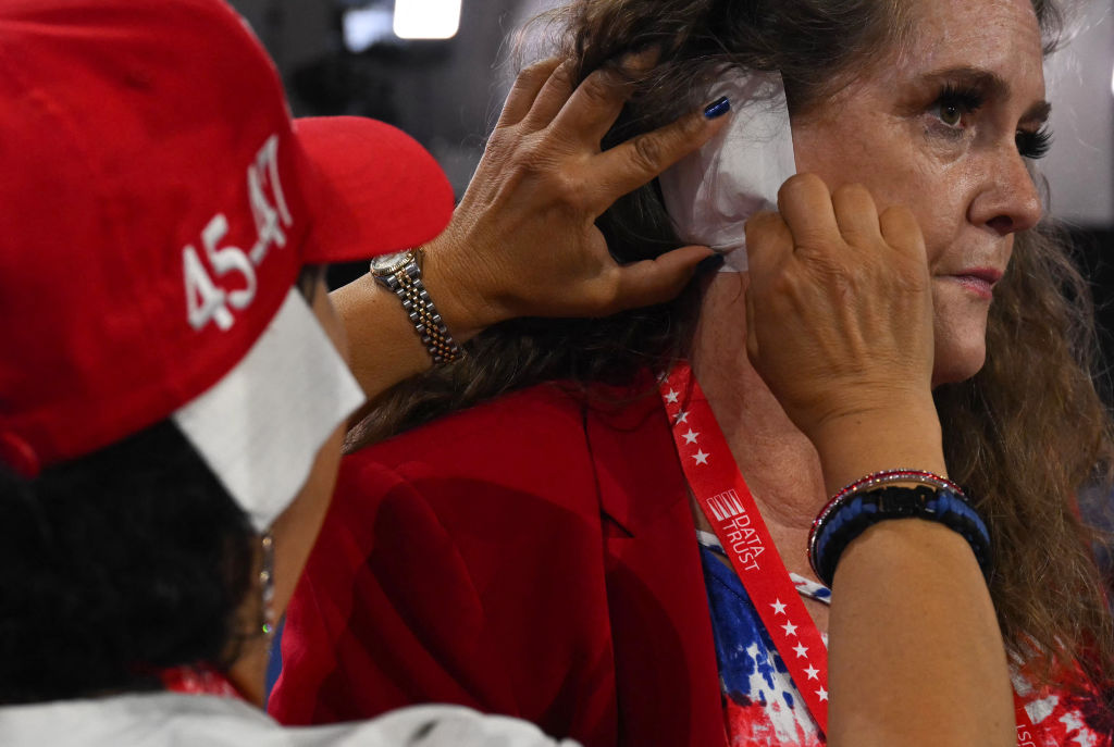 Arizona delegate Stacey Goodman (L) helps Arizona National Committeewoman elect Liz Harris (R) put a patch over her ear in solidarity with US former President and 2024 Republican presidential candidate Donald Trump during the third day of the 2024 Republican National Convention at the Fiserv Forum in Milwaukee, Wisconsin, on July 17, 2024.