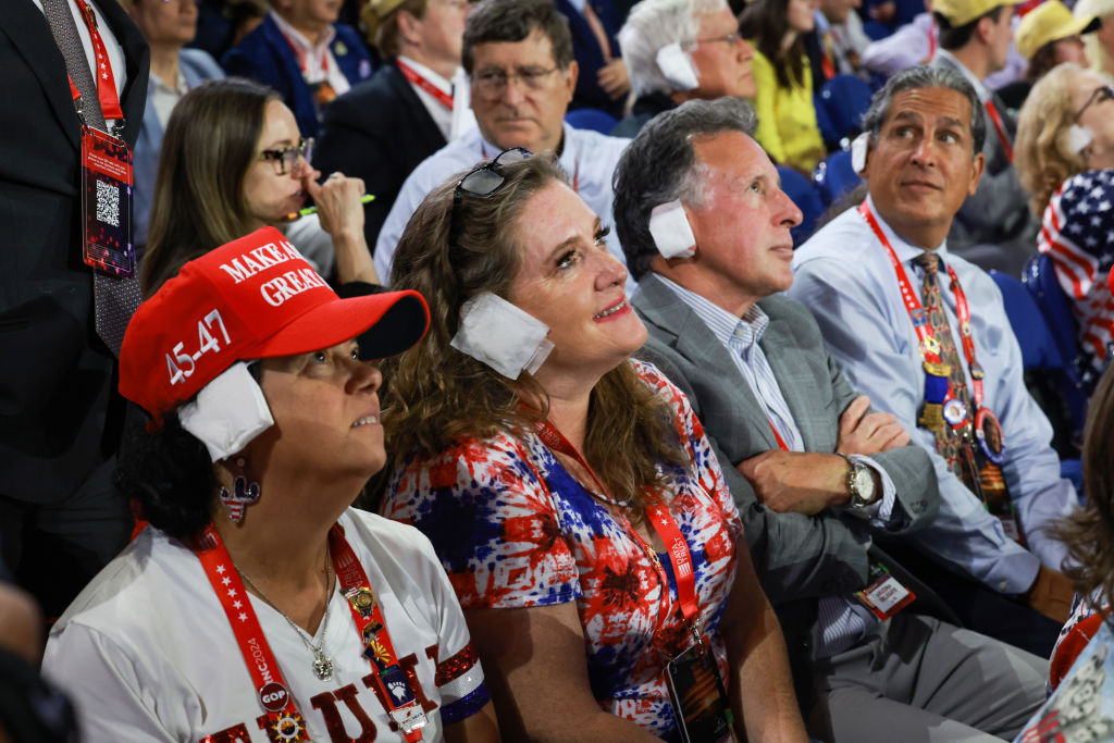 People wear "bandages" on their ears as they watch on the third day of the Republican National Convention at the Fiserv Forum on July 17, 2024 in Milwaukee, Wisconsin.