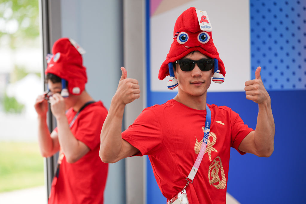 Chinese diver Yang Hao (R) wears a hat featuring the Phryges, the official mascot of Paris 2024 Olympic and Paralympic Games, at a souvenir store inside the Olympic Village on July 21, 2024 in Paris, France.