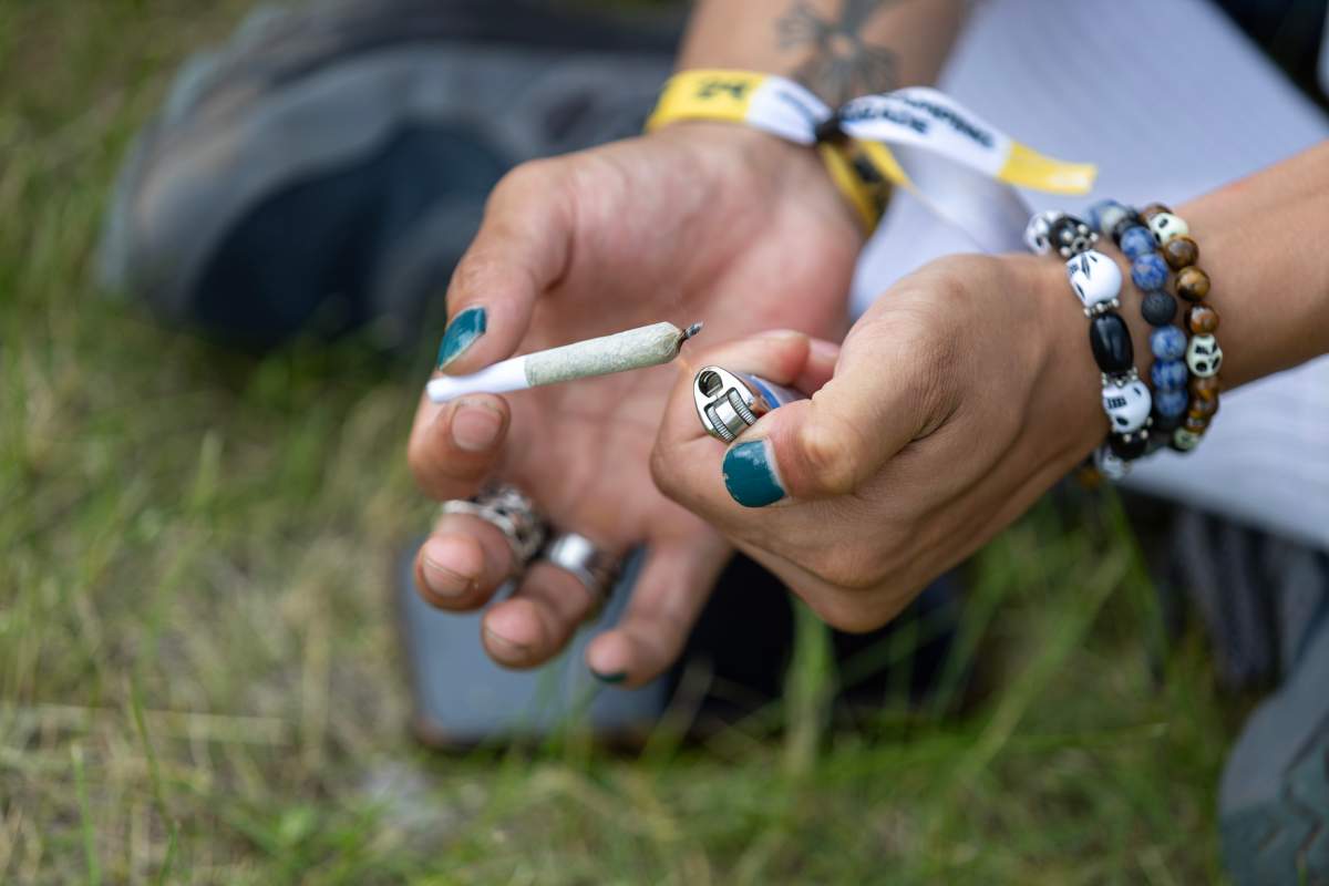 An attendee at the 2024 Winnipeg Folk Festival lights a joint