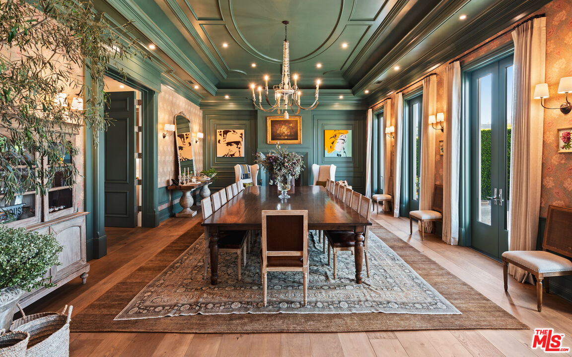 A dining room with green walls and pink floral wall paper.