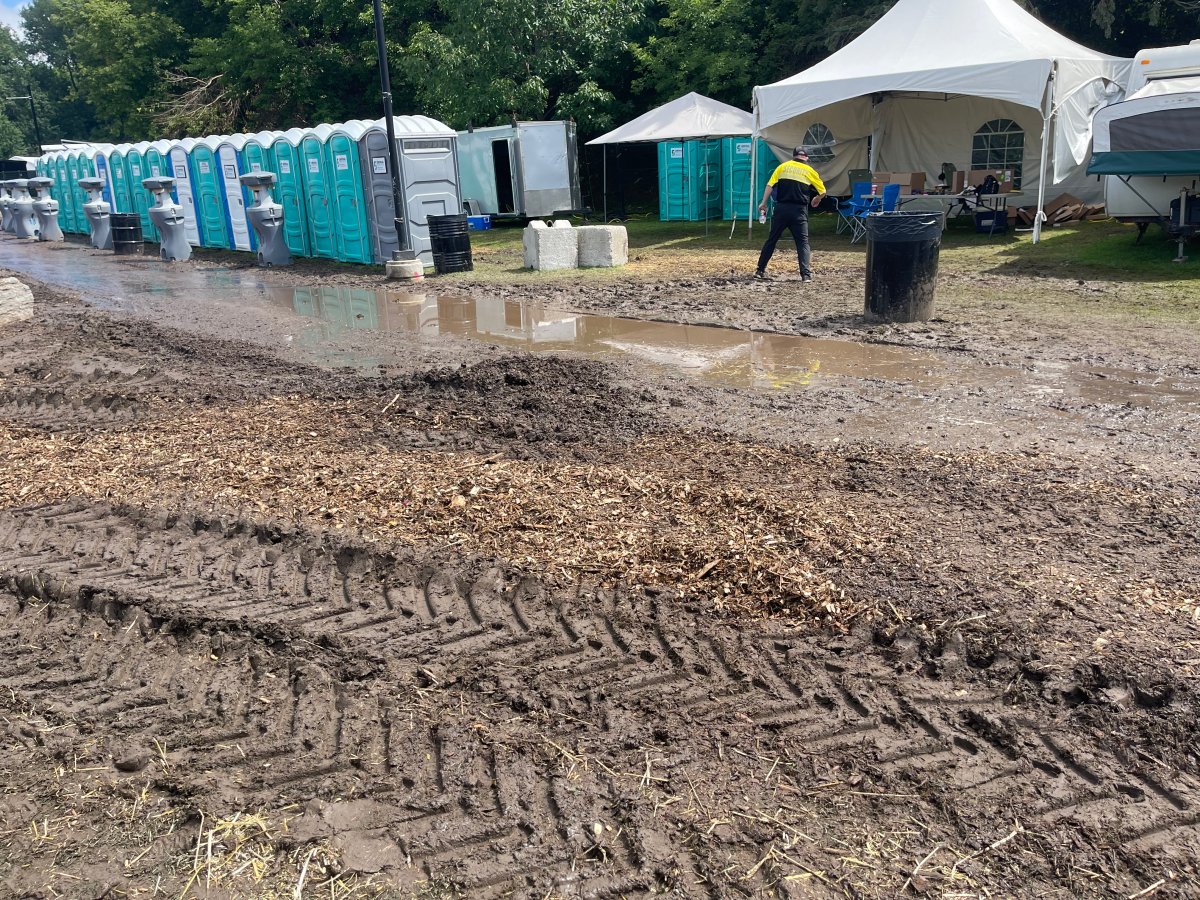 Mud in front of a muddy puddle and portable toilets in a park.
