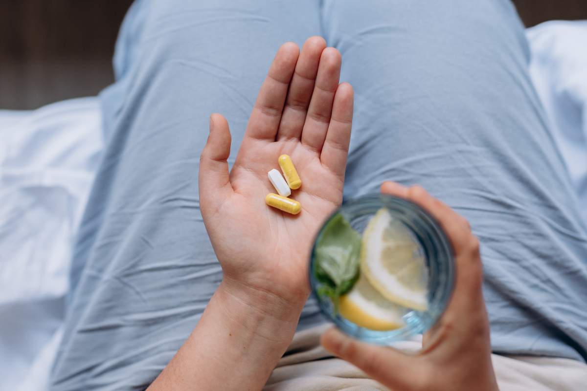 Woman Holds Capsules and Glass of Water.