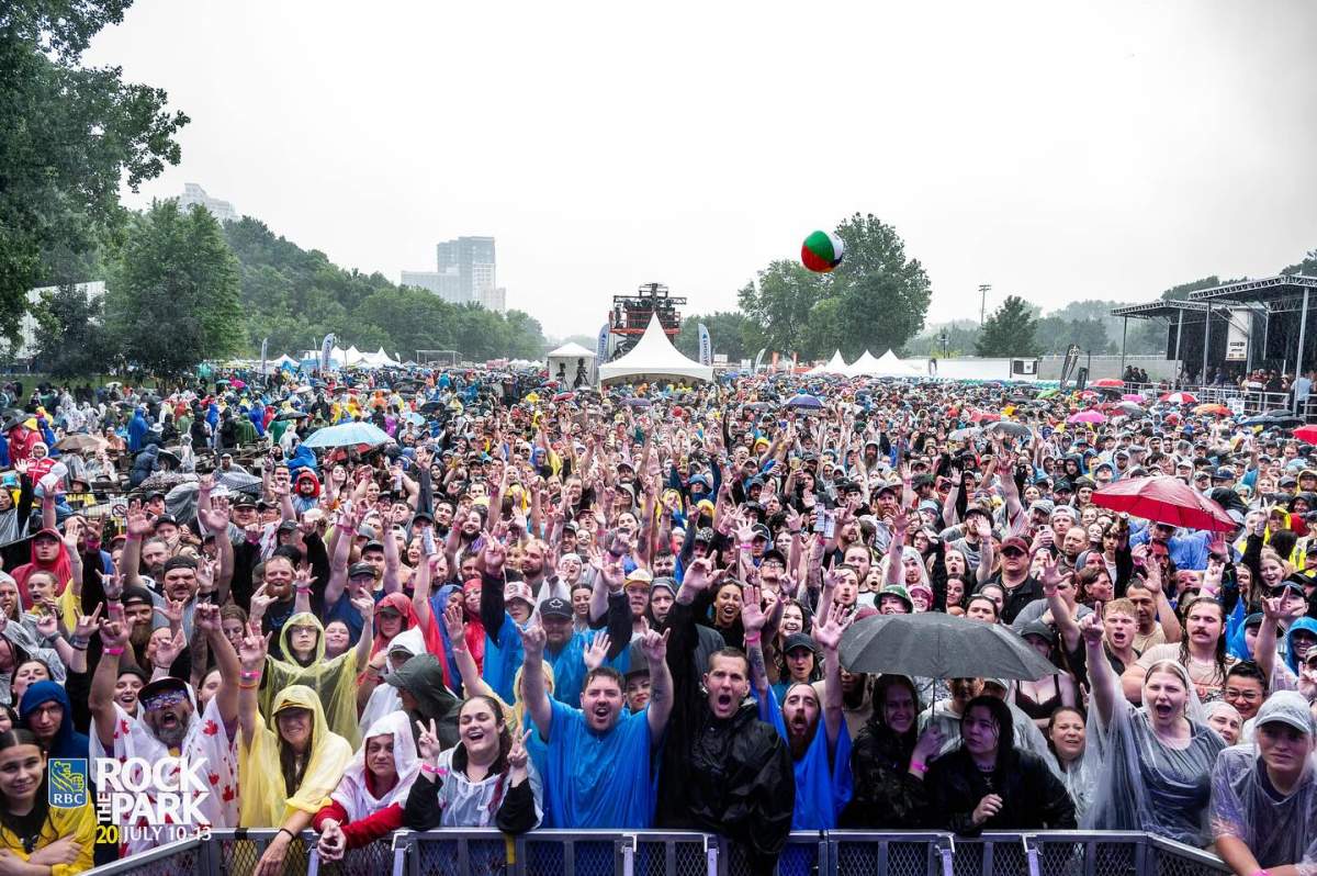 Thousands of people, mostly in ponchos, in an outdoor concert crowd on a rainy day.