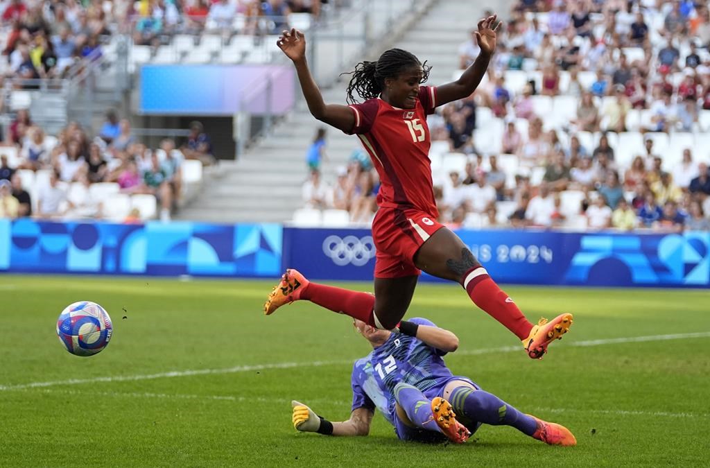 Canada's Nichelle Prince jumps over Germany goalkeeper Ann-Katrin Berger during a women's quarterfinal soccer match between Canada and Germany at the 2024 Summer Olympics, Saturday, Aug. 3, 2024, at Marseille Stadium in Marseille, France. THE CANADIAN PRESS/AP-Julio Cortez.