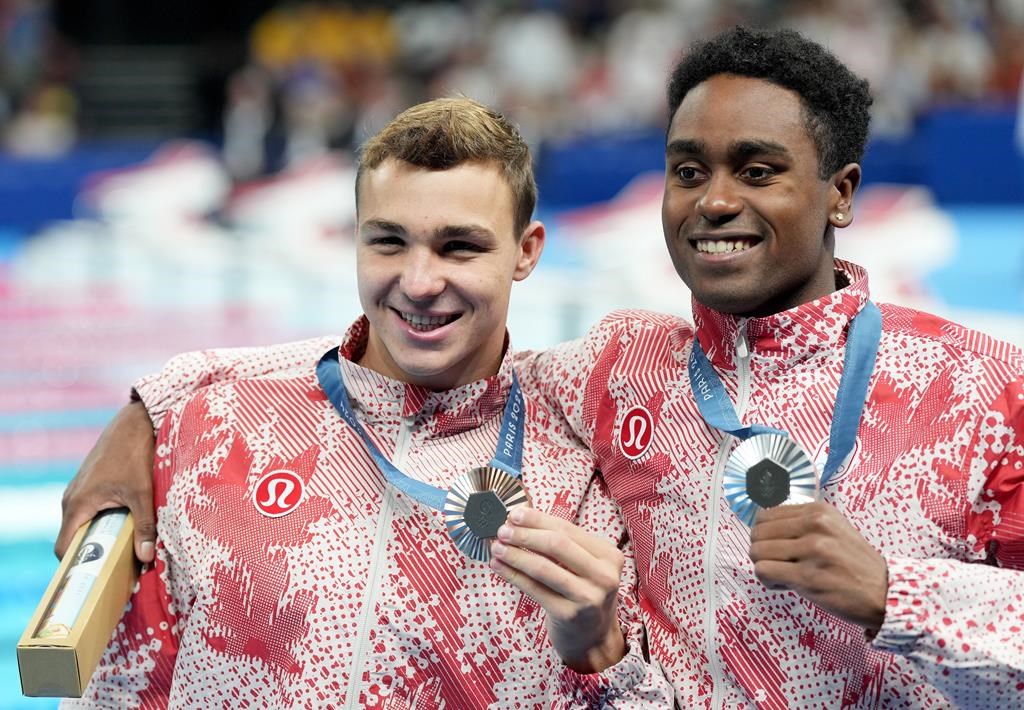 Canada's Josh Liendo, right, of Toronto, poses with the silver medal he won alongside fellow Canadian Ilya Kharun, of Montreal, who won bronze, both in the 100m men's butterfly final during the 2024 Summer Olympic Games, in Nanterre, France, Saturday, Aug. 3, 2024. THE CANADIAN PRESS/Christinne Muschi.