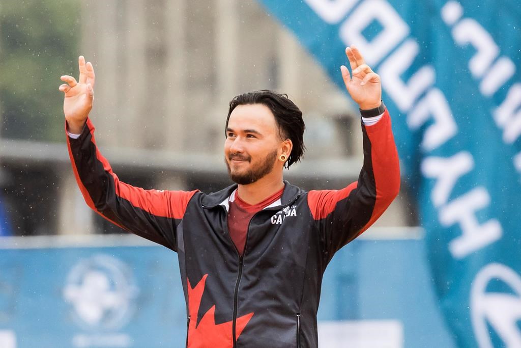 Silver medallist Eric Peters from Canada waves during the award ceremony for the men's Olympic recurve bow individual competition at the Archery World Championship in Berlin, Germany, Sunday, Aug. 6, 2023. (Christoph Soeder/dpa via AP).