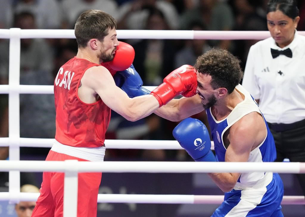 Canada's Wyatt Sanford, left, trades punches with Sofiane Oumiha of France in the men's 63.5 kg semifinal boxing match at the 2024 Summer Olympics, Sunday, Aug. 4, 2024, in Paris, France. THE CANADIAN PRESS/Christinne Muschi.