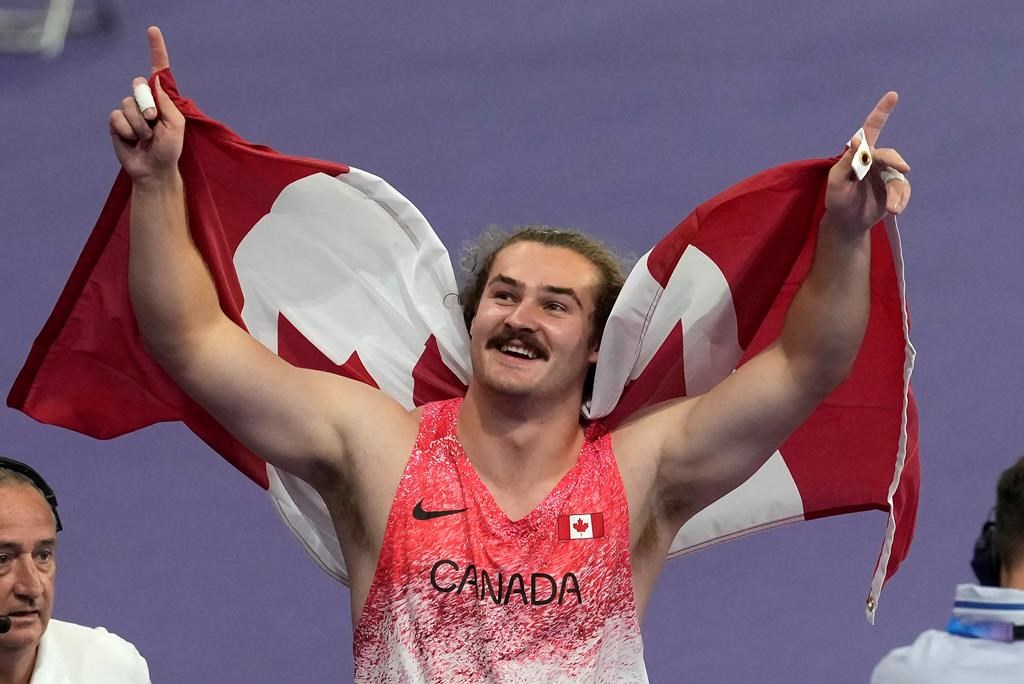 Ethan Katzberg, of Nanaimo, B.C., celebrates after winning gold in the men's hammer throw event at the 2024 Summer Olympics, Sunday, Aug. 4, 2024, in Saint-Denis, France. THE CANADIAN PRESS/Adrian Wyld.