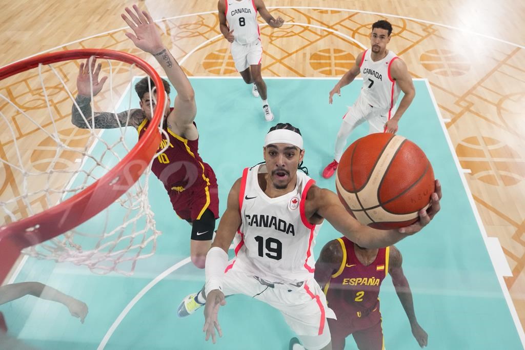 Andrew Nembhard, of Canada, shoots in front of Juancho Hernangomez, left, and Lorenzo Brown, of Spain, in a men's basketball game at the 2024 Summer Olympics, Friday, Aug. 2, 2024, in Villeneuve-d'Ascq, France. THE CANADIAN PRESS/AP-Mark J. Terrill.