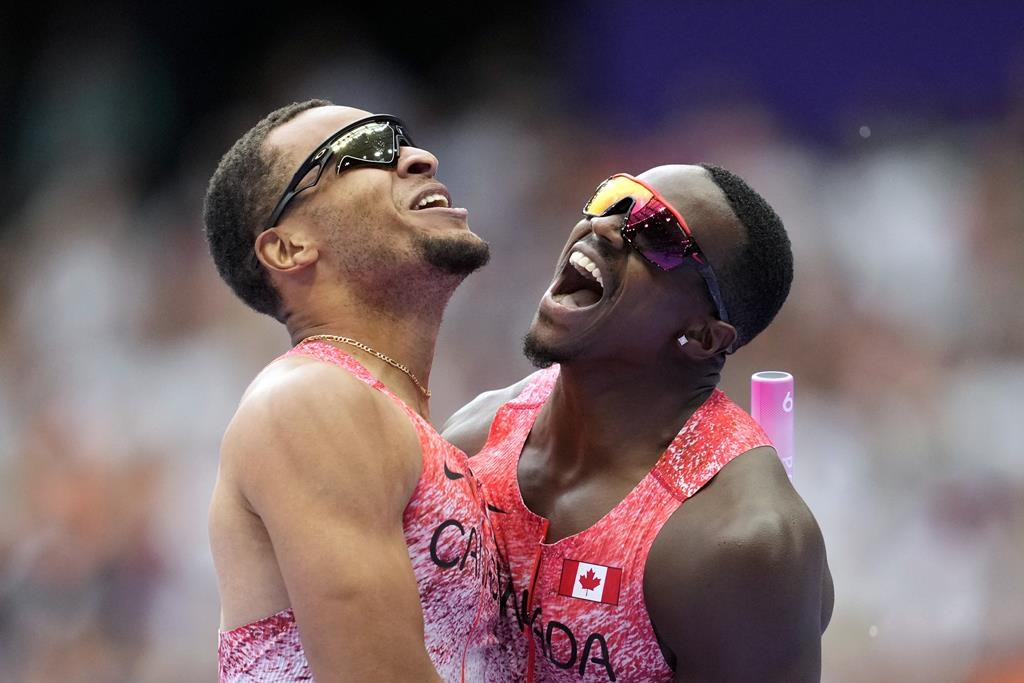 Aaron Brown, right, and Andre de Grasse, of Canada, celebrate after winning the gold medal in the men's 4 x 100 meters relay final at the 2024 Summer Olympics, Friday, Aug. 9, 2024, in Saint-Denis, France. Canada's men's 4x100-metre relay team claimed Olympic gold on Friday night at Stade de France in a stellar performance from Lane 9. With Andre De Grasse running the anchor leg, the Canadians posted a winning time of 37.50 seconds. (AP Photo/Ashley Landis).