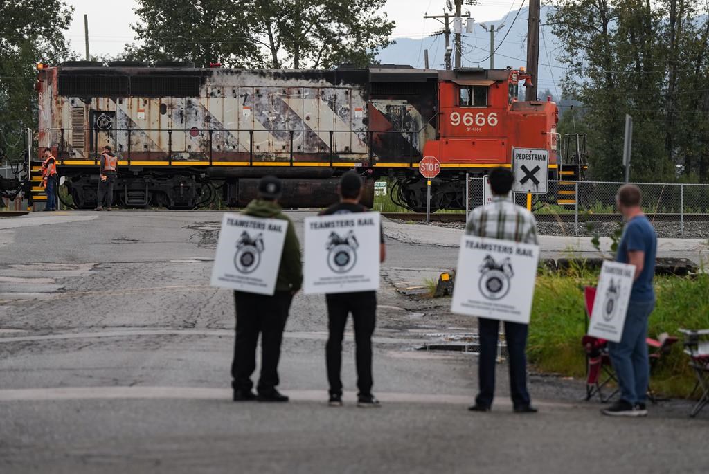 Locked out Canadian National Rail workers stand at a picket line as locomotives are moved by management at CN Rail’s Thornton Yard, in Surrey, B.C., on Thursday, August 22, 2024. In the culmination of months of increasingly bitter negotiations, Canadian National Railway Co. and Canadian Pacific Kansas City Ltd. locked out 9,300 engineers, conductors and yard workers after the parties failed to agree on a new contract before the midnight deadline. THE CANADIAN PRESS/Darryl Dyck