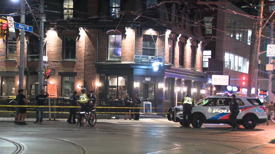 Police caution tape, vehicles and personnel at an intersection in Toronto at night.