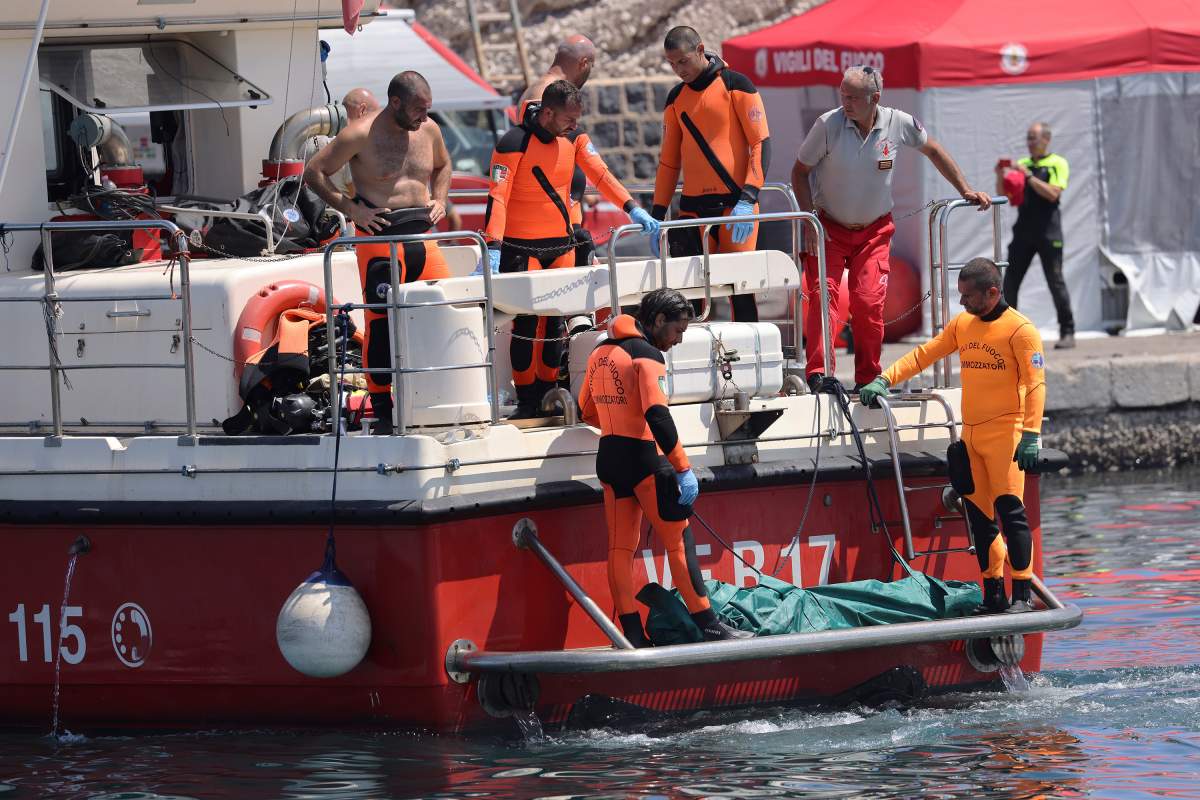 Italian firefighter divers bring ashore a plastic body bag containing one of the victims of a shipwreck, in Porticello, Sicily, southern Italy, Friday Aug. 23, 2024. Italian rescuers brought ashore the body of the final missing person who was on a superyacht that sunk off the coast of Sicily.