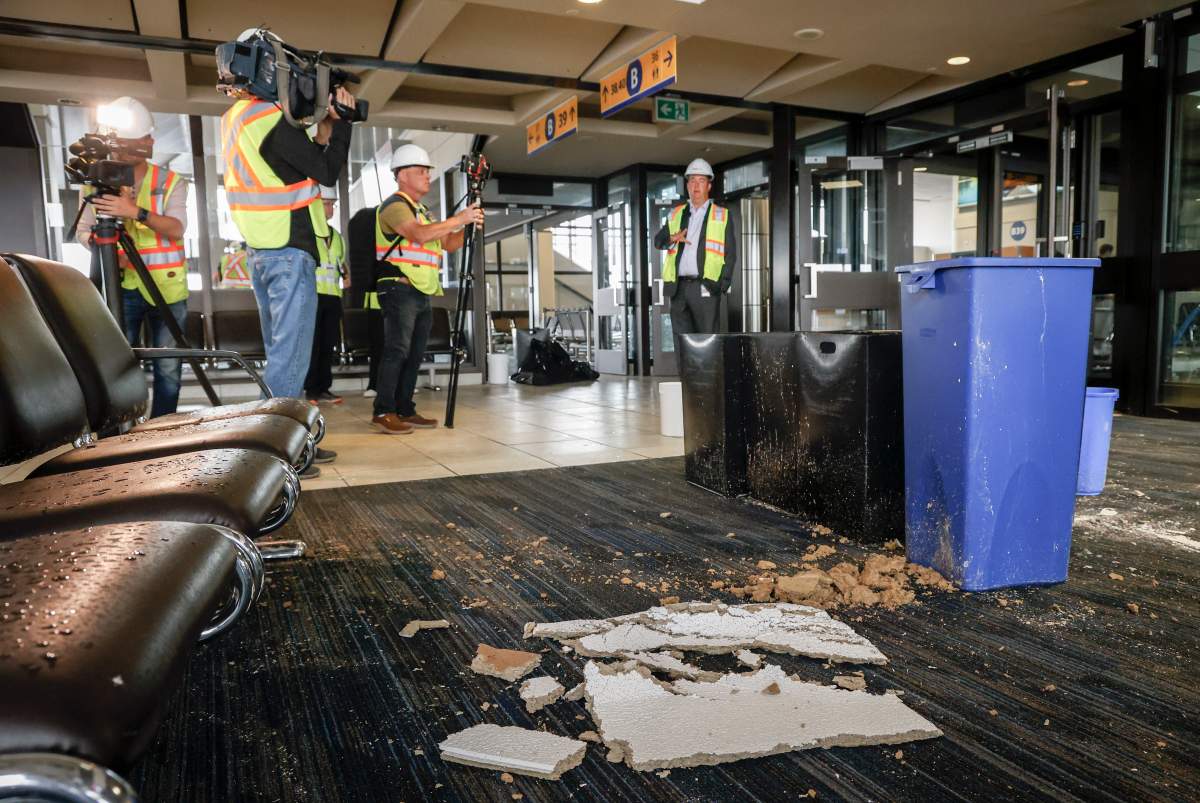 Chris Miles, right, Chief Operating Officer, of the Calgary Airport, speaks to members of the media on a tour of a closed concourse as repairs are underway at the Calgary International Airport after parts of its domestic terminal building were closed late Monday due to damage caused by hail and heavy rainfall, in Calgary, Alta., Tuesday, Aug. 6, 2024.
