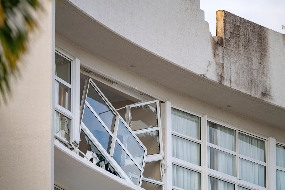 A broken window hands precariously at the Double Tree by Hilton Hotel in Cairns, Australia, after a helicopter crashed into its roof early Monday, Aug. 12, 2024.