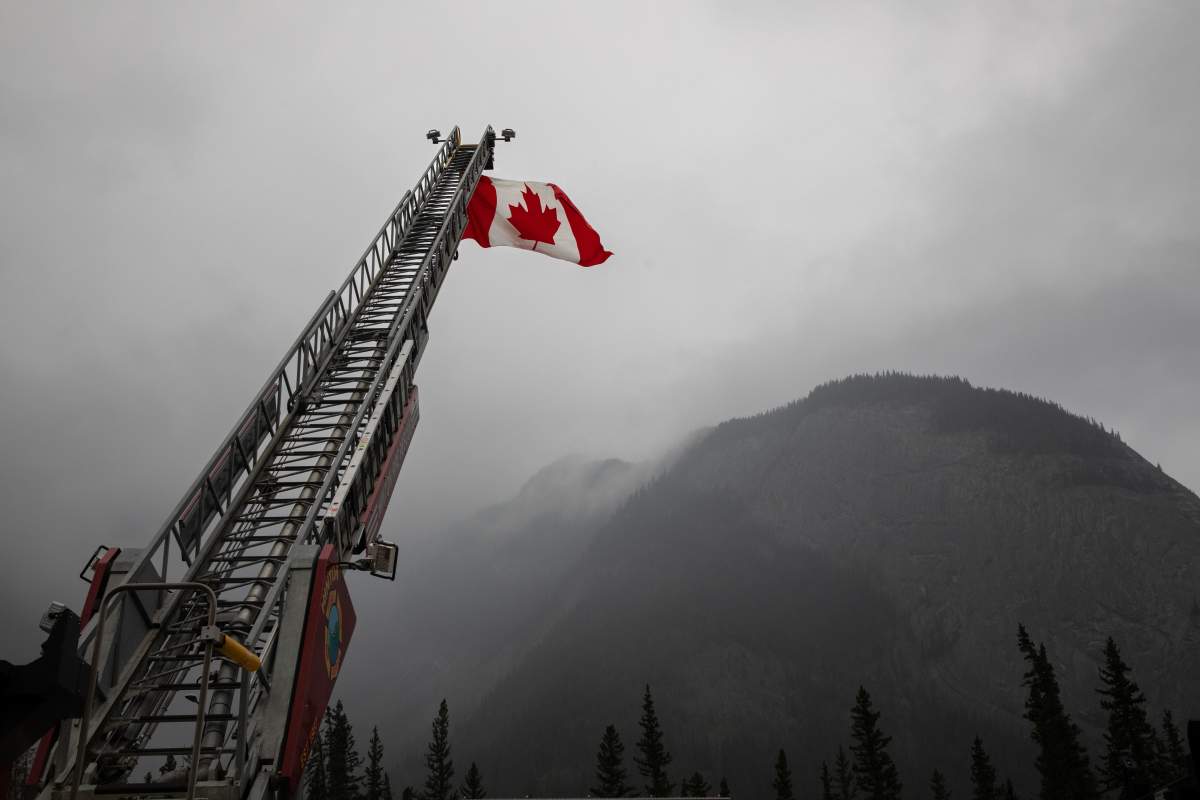A Canadian flag hangs over the highway on on the first day residents are able to visit their properties in Jasper, Alberta on Friday August 16, 2024. Wildfire caused evacuations and widespread damage in the National Park and Jasper townsite.