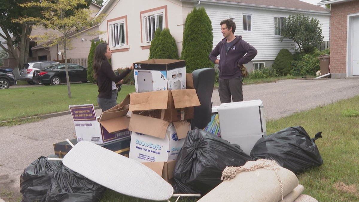 Kaspar Schattke stands with his drenched belongings in front of his home in Sainte-Anne-de-Bellevue on Aug. 12, 2024.