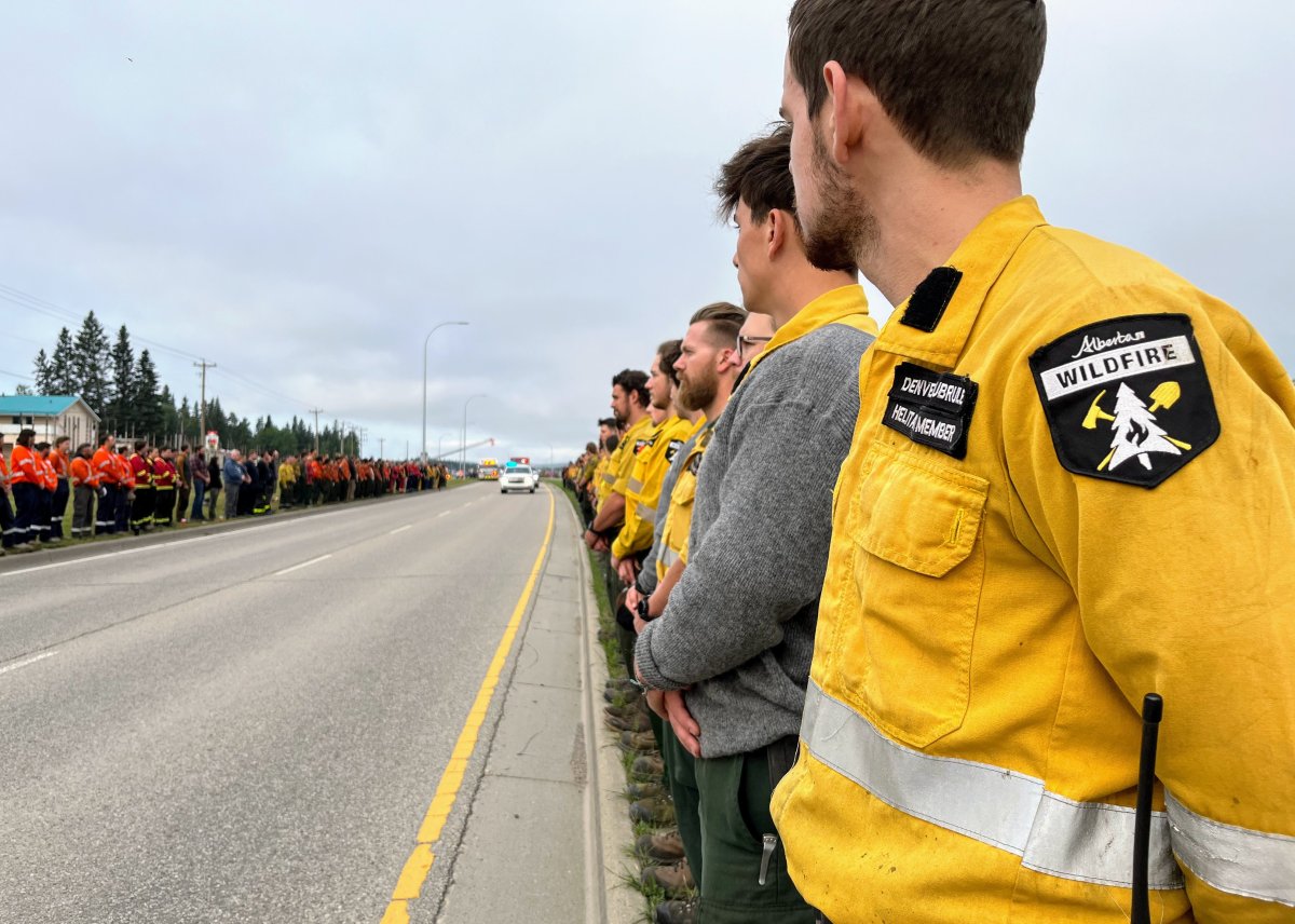 Alberta wildfire members watch a procession pass by for a firefighter who died fighting the Jasper wildfires.