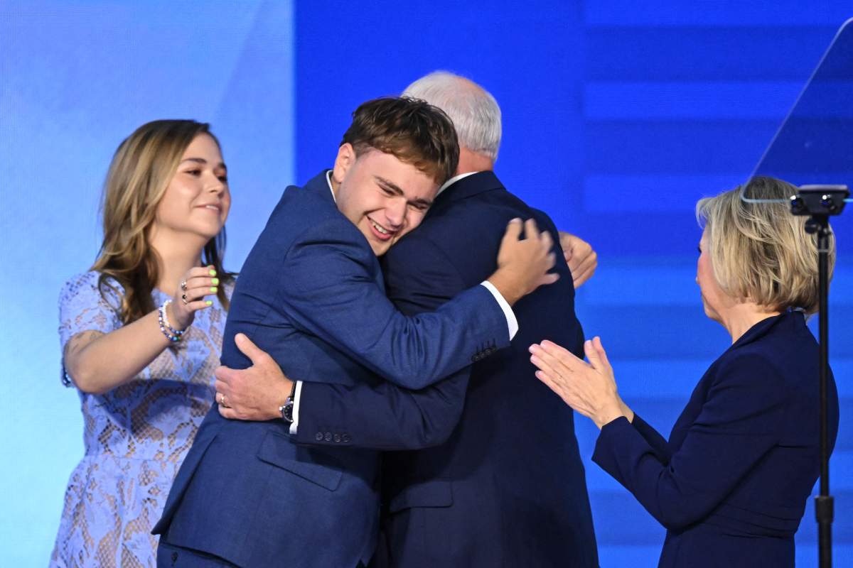 After concluding his remarks, Minnesota Governor and Democratic vice presidential candidate Tim Walz is embraced by his son Gus (second from the left) as daughter Hope (left) and wife Gwen Walz (right) look on during the third day of the Democratic National Convention on August 21, 2024.