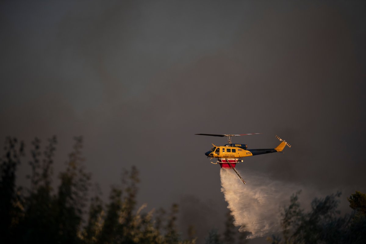 A helicopter drops water near Varnava village during a wildfire, north of Athens, Greece, Sunday, Aug. 11, 2024, with many regions of the country on high alert due to high temperatures and wind speeds. (AP Photo/Michael Varaklas)