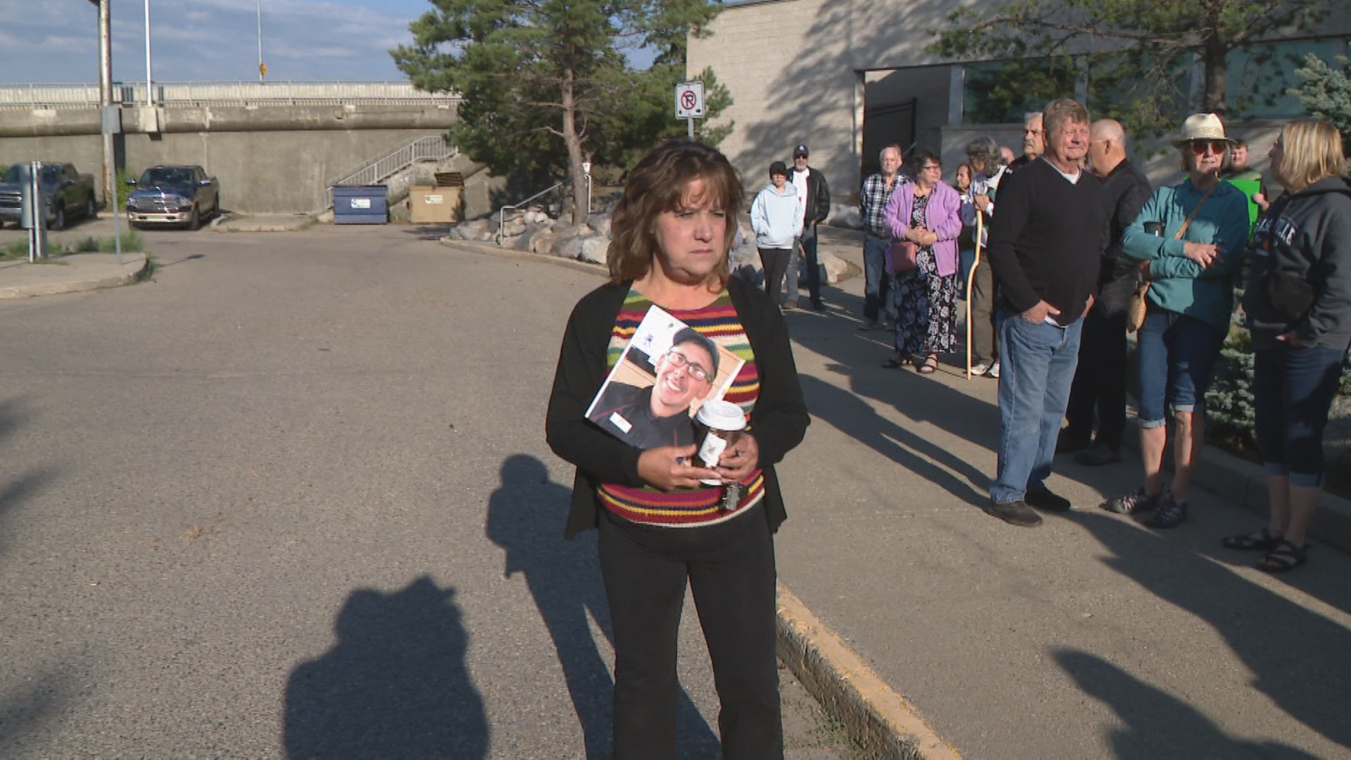 Maureen Palagian, Trevor LaPlante’s sister, holds his photo at Wedneday’s rally.