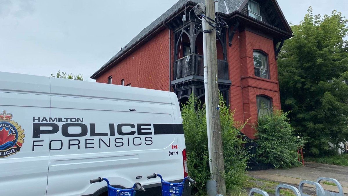 A police forensics van outside of a red bricked building on an overcast day.