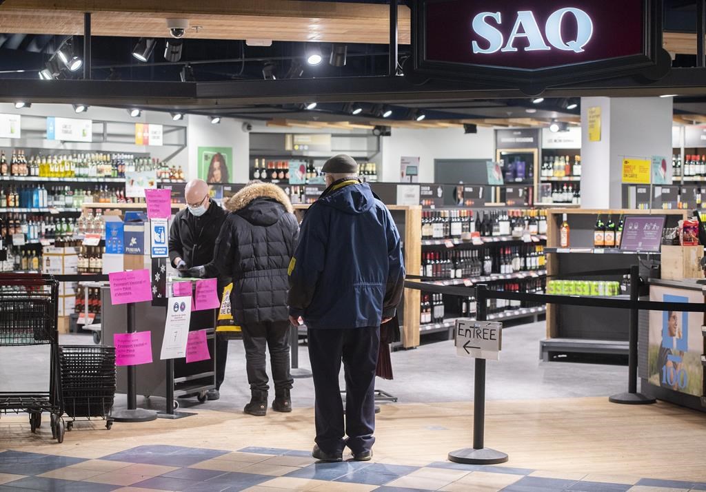 The provincial Crown corporation in charge of liquor sales in Quebec is confirming that a computer error resulted in all its products being temporarily listed at 30 per cent off on its website. People wait to enter a SAQ outlet in Montreal, Tuesday, January 18, 2022.