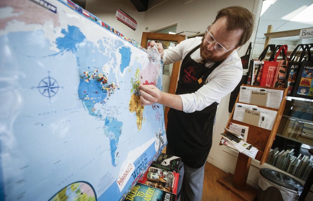 Michael Bumsted, who owns the independent bookstore Whodunit Mystery Bookstore with his mother Wendy, places a pin in Europe where his most recent foreign sale happened in their store Wednesday, Sept. 4, 2024 in Winnipeg.