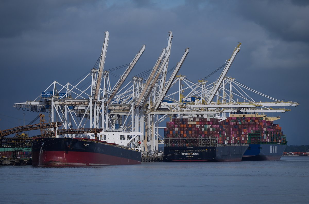 Coal is loaded onto the bulk carrier vessel Fosep at the Westshore coal export terminal at Roberts Bank as container ships are seen docked beneath gantry cranes at Deltaport, in Tsawwassen, B.C.