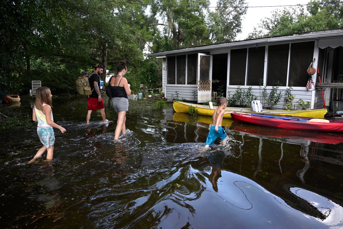 Dustin Holmes, rear, his girlfriend Hailey Morgan, and her children Aria Skye Hall, 7, left, and Kyle Ross, 4, right, arrive to their flooded home in the aftermath of Hurricane Helene, Friday, Sept. 27, 2024, in Crystal River, Fla.