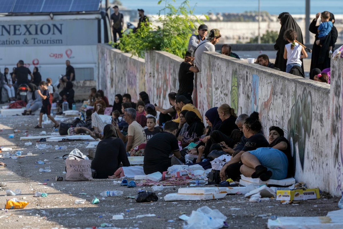 Families sit on the ground in Martyrs' square after fleeing the Israeli airstrikes in Beirut's southern suburbs, Saturday, Sept. 28, 2024.