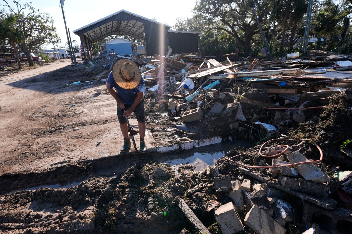 Chris Jordan, maintenance manager for Horseshoe Beach, tries to find a water shutoff valve amid the rubble of the destroyed city hall in the aftermath of Hurricane Helene, in Horseshoe Beach, Fla., Sunday, Sept. 29, 2024.