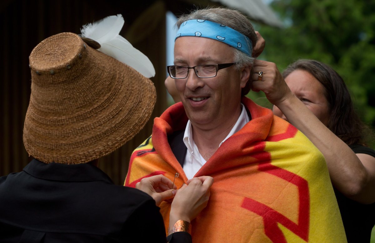 British Columbia's then minister of aboriginal relations and reconciliation John Rustad, centre, is wrapped in a blanket by Carrielynn Victor, left, of the Cheam First Nation, as Leanne Quipp puts on a headband before a ceremony to mark the signing of an agreement between the government and 14 Sto:lo First Nations in Chilliwack, B.C., on June 19, 2014