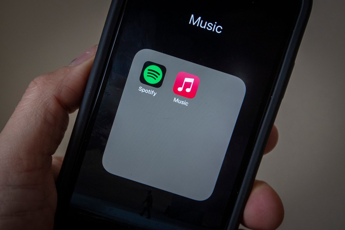 A smartphone showing a folder called "Music" with the Spotify and Apple Music apps inside.