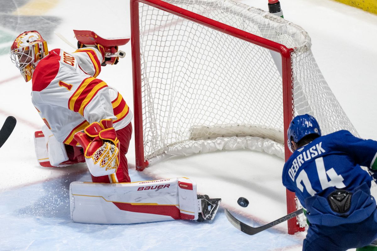 Vancouver Canucks' Jake DeBrusk (74) scores on Calgary Flames goaltender Devin Cooley (1) during overtime NHL pre-season hockey action in Abbotsford, B.C., on Wednesday September 25, 2024.