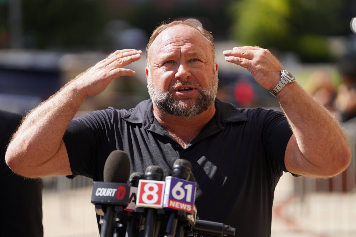 Alex Jones speaking at a microphone.