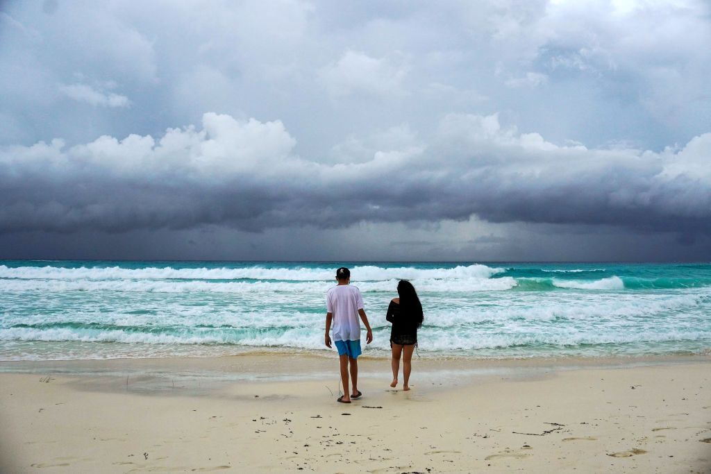 Storm clouds are pictured as a couple walks on the beach ahead of the arrival of tropical storm Helene in Cancun, Quintana Roo state, Mexico on September 24, 2024.