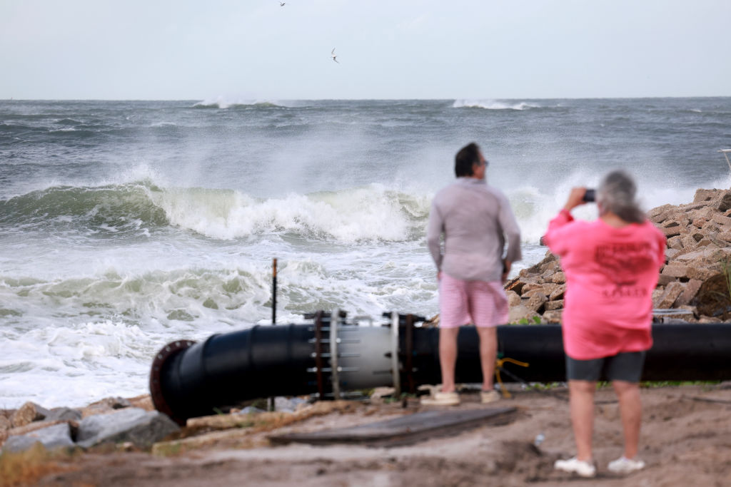 People look out at the waves from the Gulf of Mexico pushing up against the shore as Hurricane Helene churns offshore on September 26, 2024 in St. Pete Beach, Florida. Later today, Helene is forecast to become a major hurricane, bringing the potential for deadly storm surges, flooding rain, and destructive hurricane-force winds along parts of the Florida West Coast.