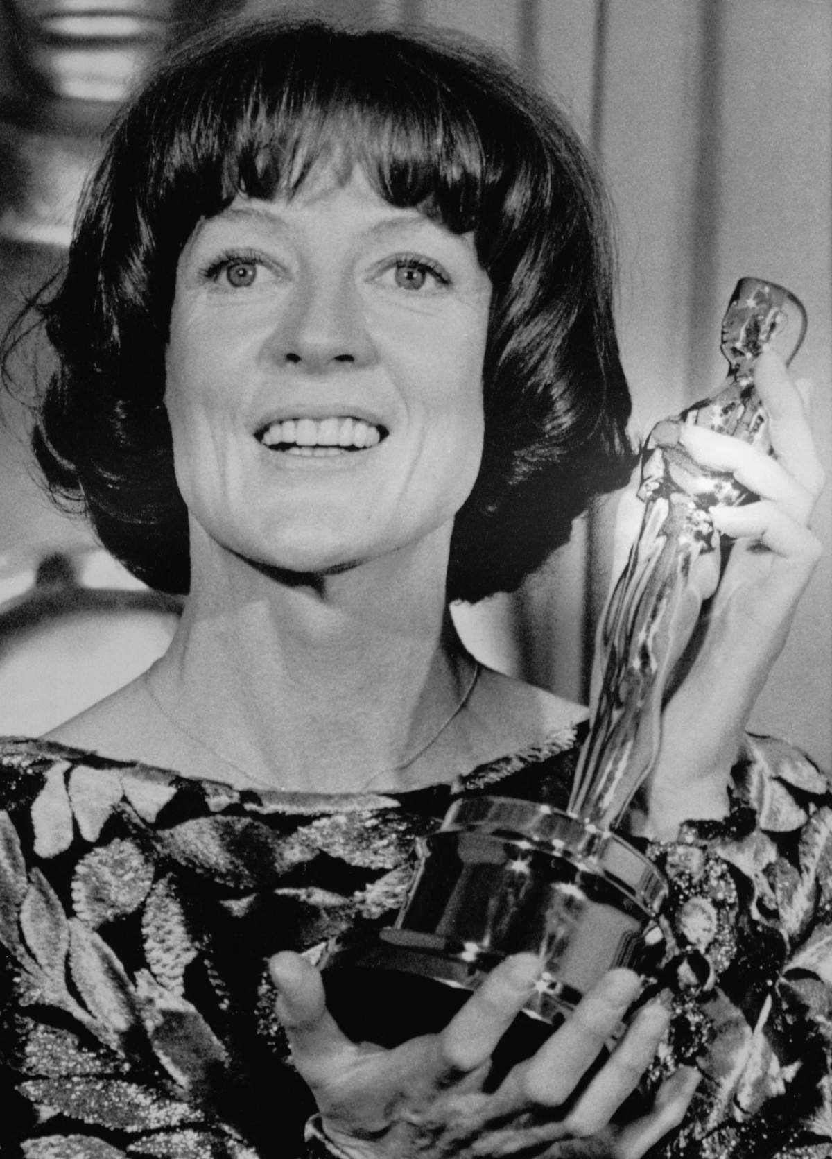Dame Maggie Smith holding an Oscar.