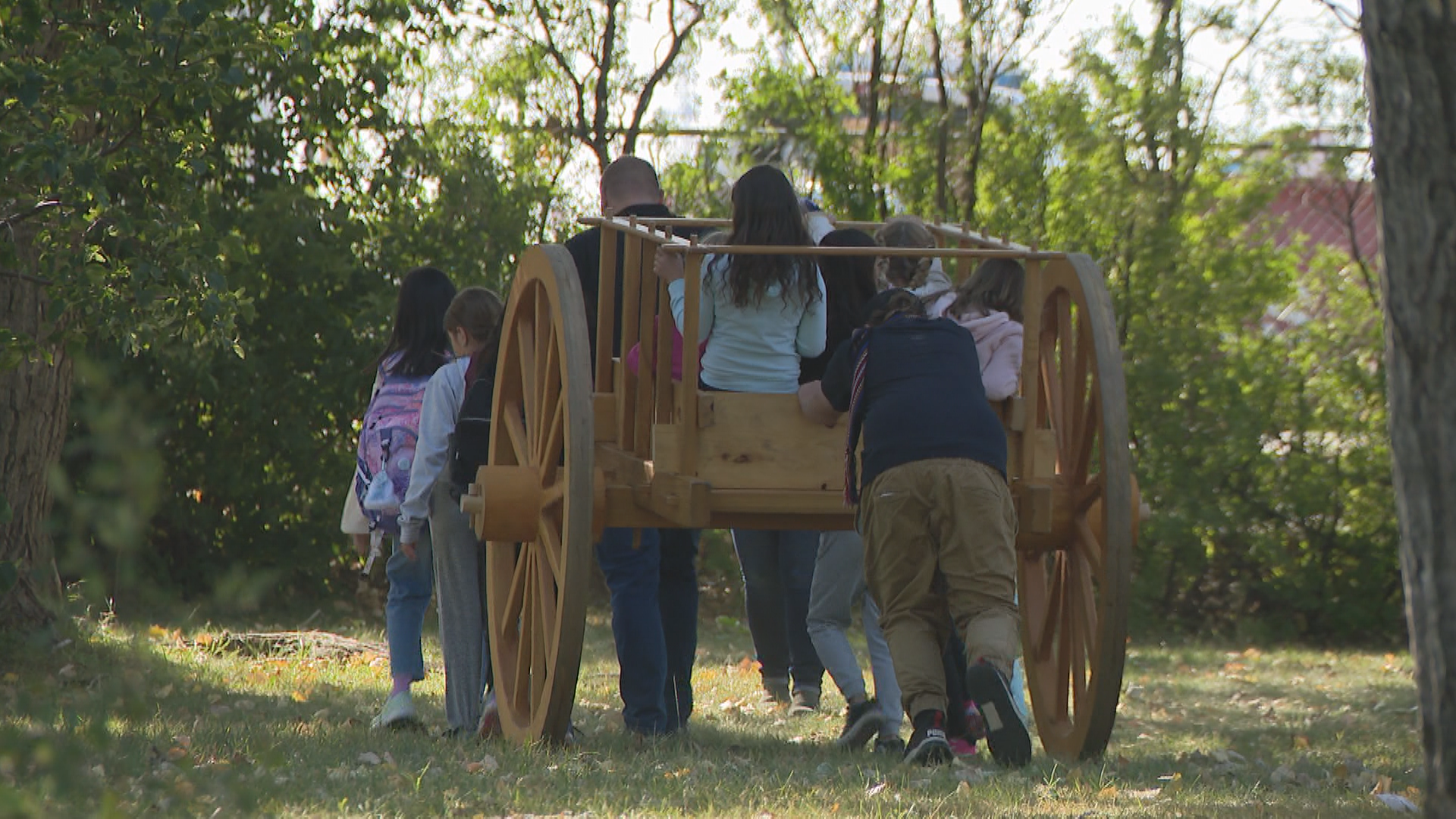 A Red River cart being pushed by students.