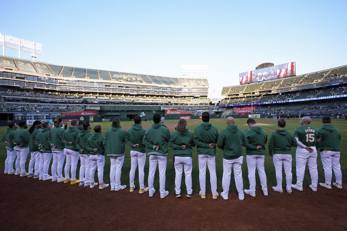 The Oakland Athletics listen to the national anthem before a baseball game against the Texas Rangers, Tuesday, Sept. 24, 2024, in Oakland, Calif.