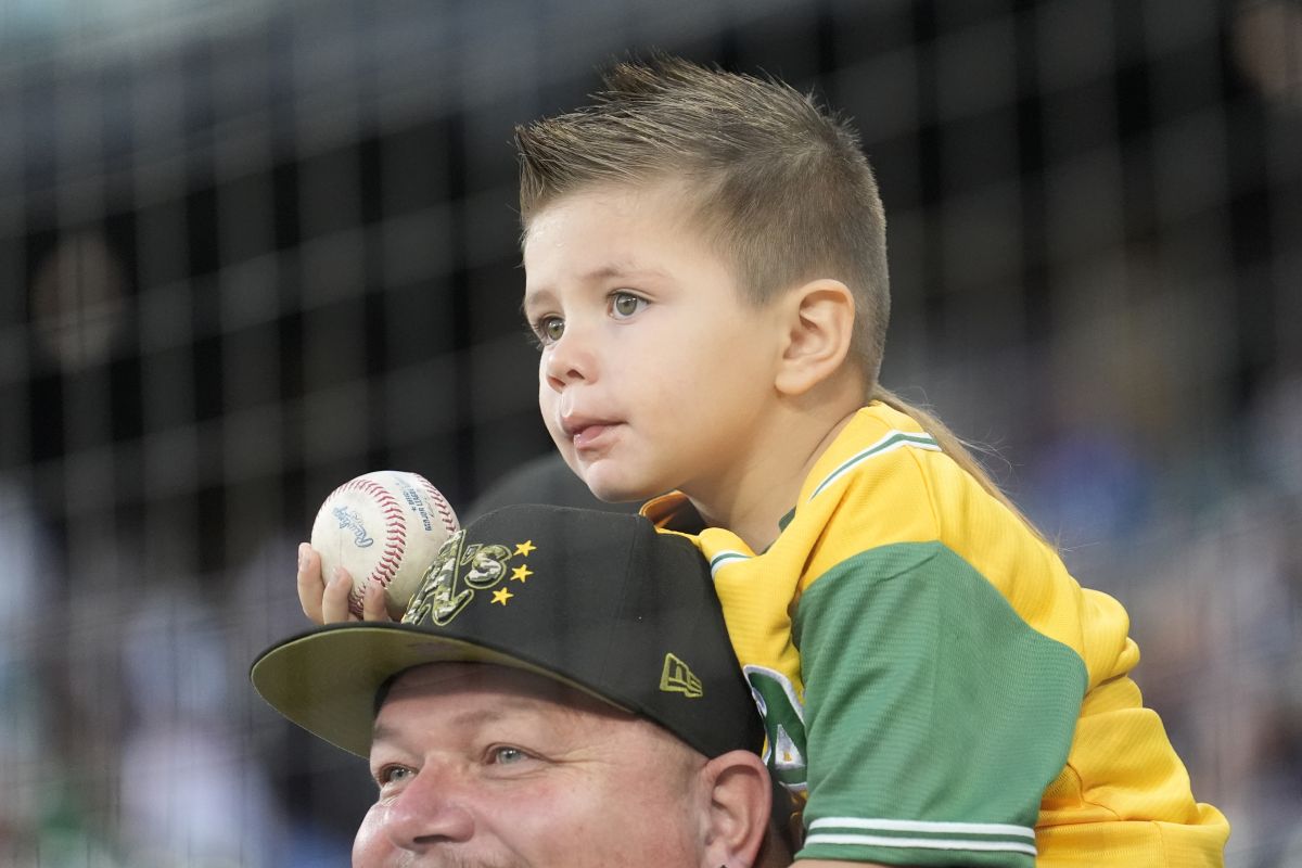 Oakland Athletics fan Joel Lira Jr., sits on the shoulders of his father Joel Sr., from Fremont, Calif., hoping for an autograph before a baseball game between the Chicago White Sox and the A's Friday, Sept. 13, 2024, in Chicago.